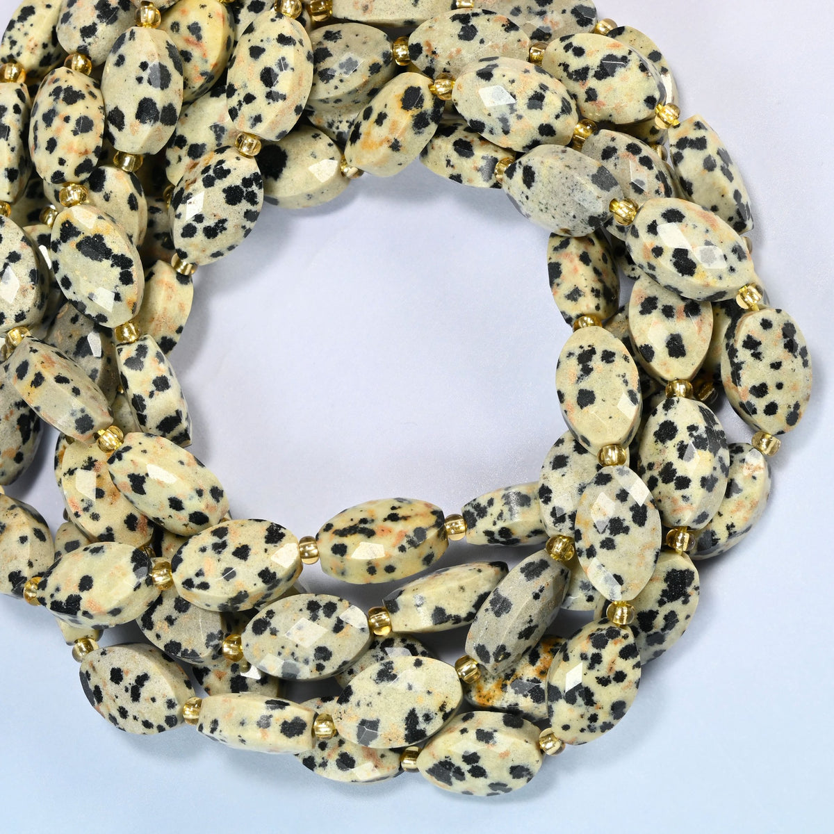 Dalmatian jasper faceted flat oval beads coiled into overlapping loops, whole strands of black-spotted cream stone