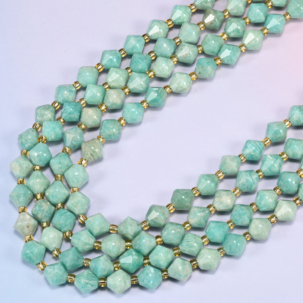 Green Amazonite faceted bicone beads 8mm with gold-tone spacers, strand draped in a loose diagonal curve