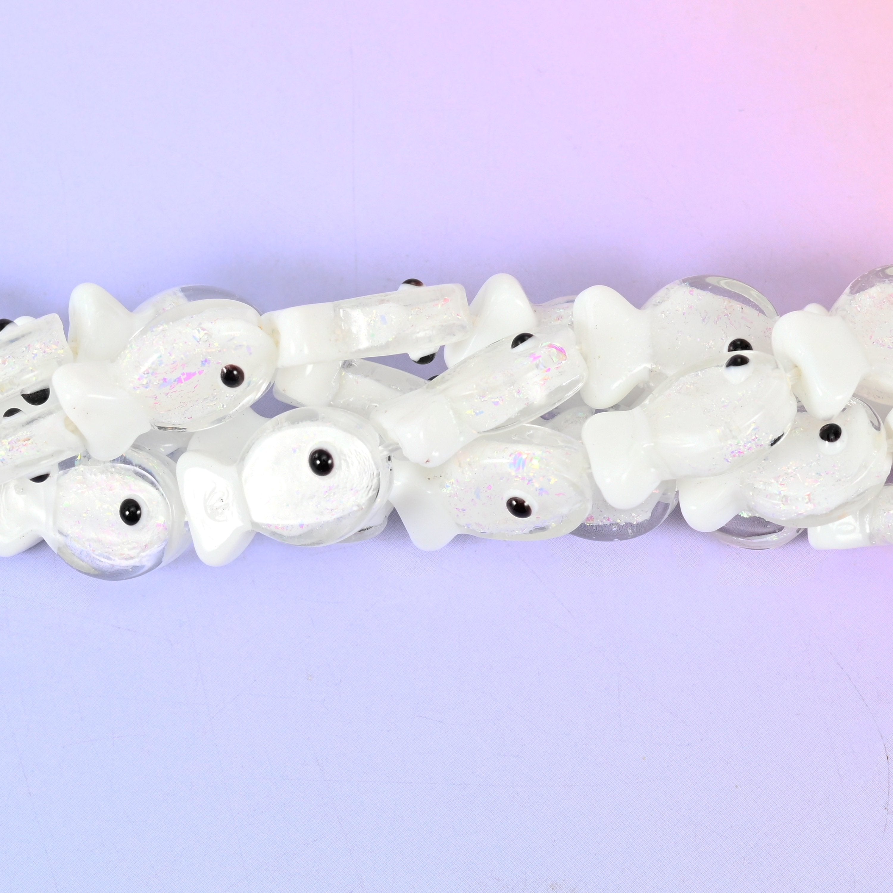 Iridescent White Fish Glass Beads — a milky opal-white fish with a faint pearl shimmer running across its body, a translucent flared tail and a small black eye dot.