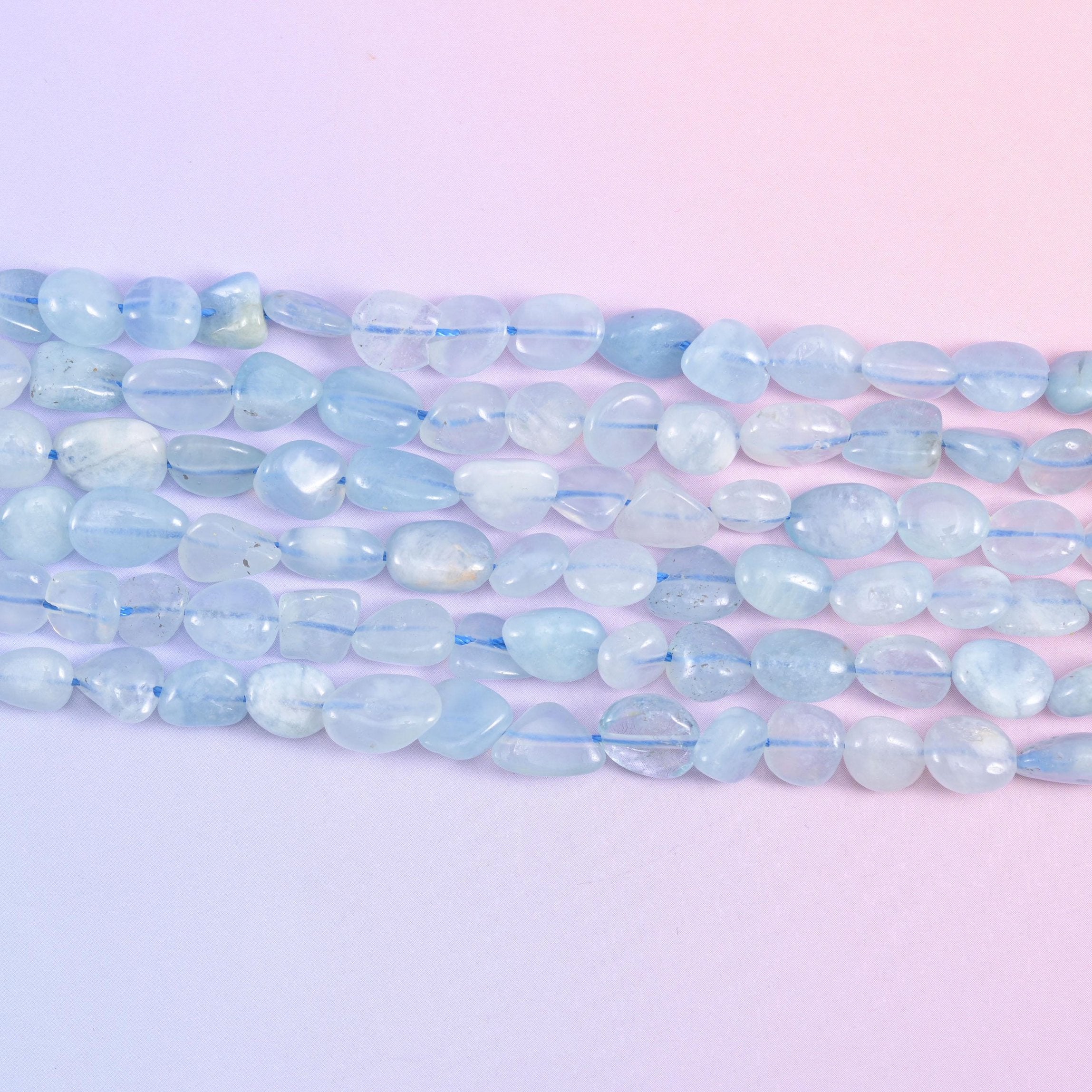 Close row of smooth polished aquamarine nuggets in milky sky blue and white