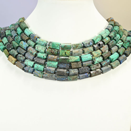 Azurite chrysocolla faceted tube strands arranged as a layered collar on a white display bust, turquoise green and brown beads across the neck