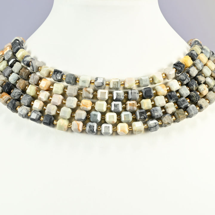 Picasso jasper faceted cube strands arranged as a layered collar on a white display bust, cream, gray and charcoal beads across the neck