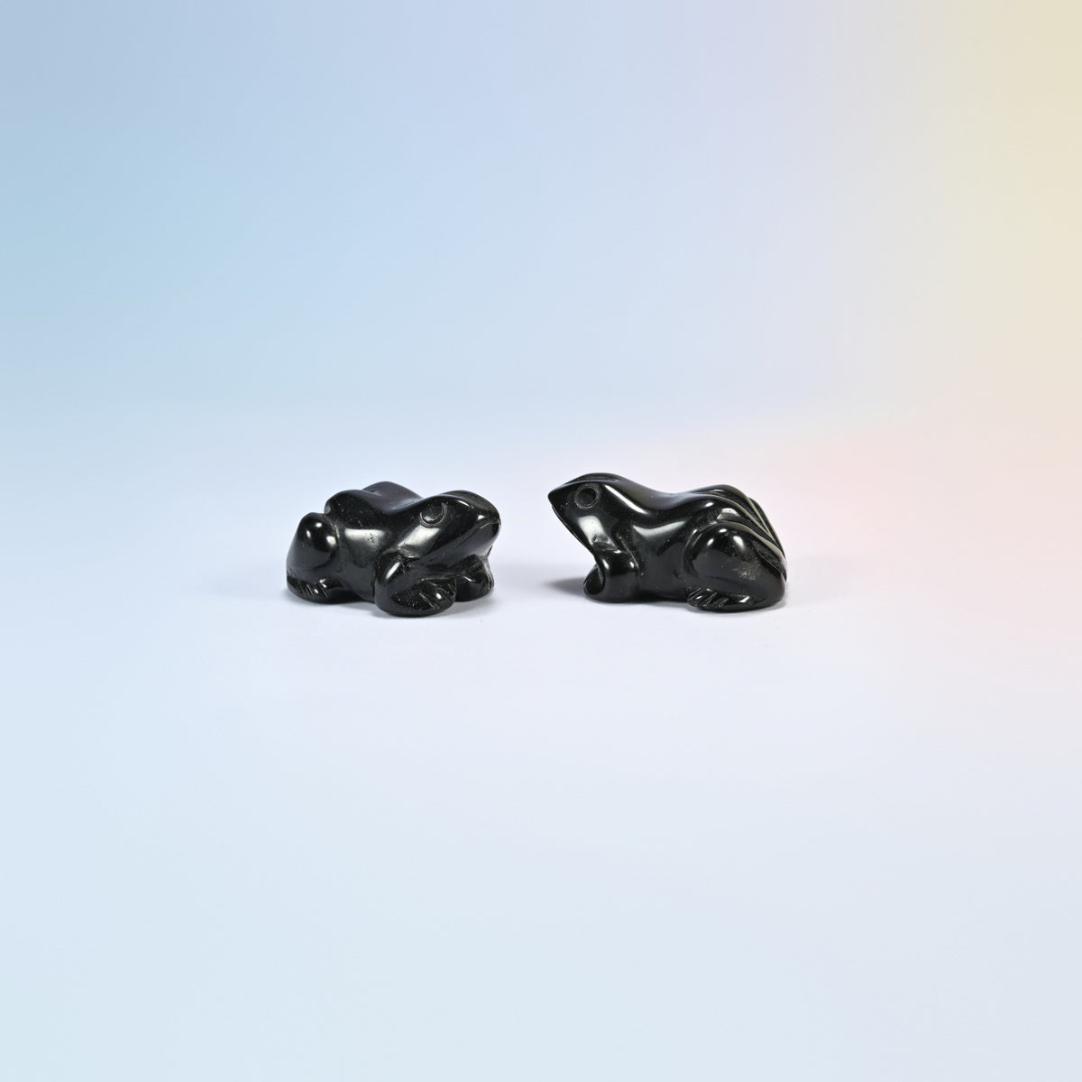 Two natural black obsidian frog carvings, glossy black with round eyes