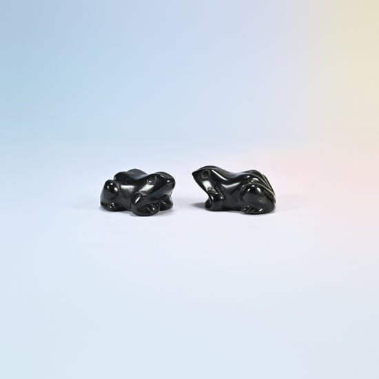 Two natural black obsidian frog carvings, glossy black with round eyes