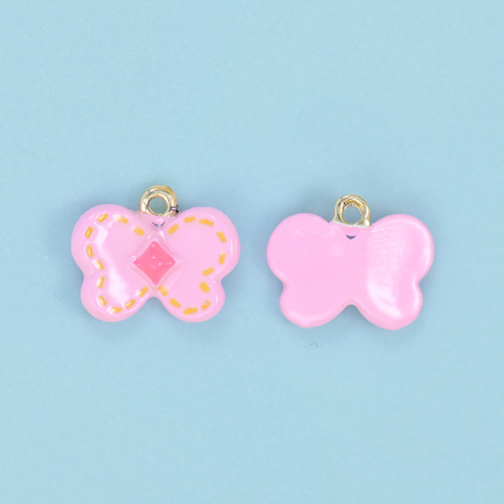Pink butterfly charms shown front and back, orange dotted wing outline and a pink centre diamond.