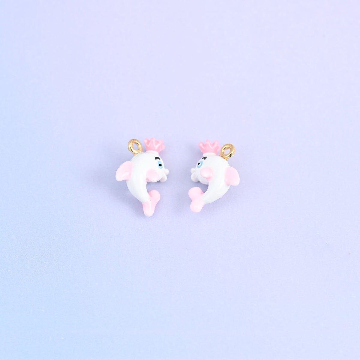 Two white dolphin charms with crowns, front and back, pink crown and a blue painted eye.