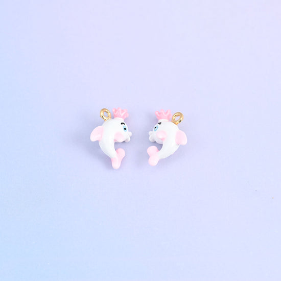 Two white dolphin charms with crowns, front and back, pink crown and a blue painted eye.