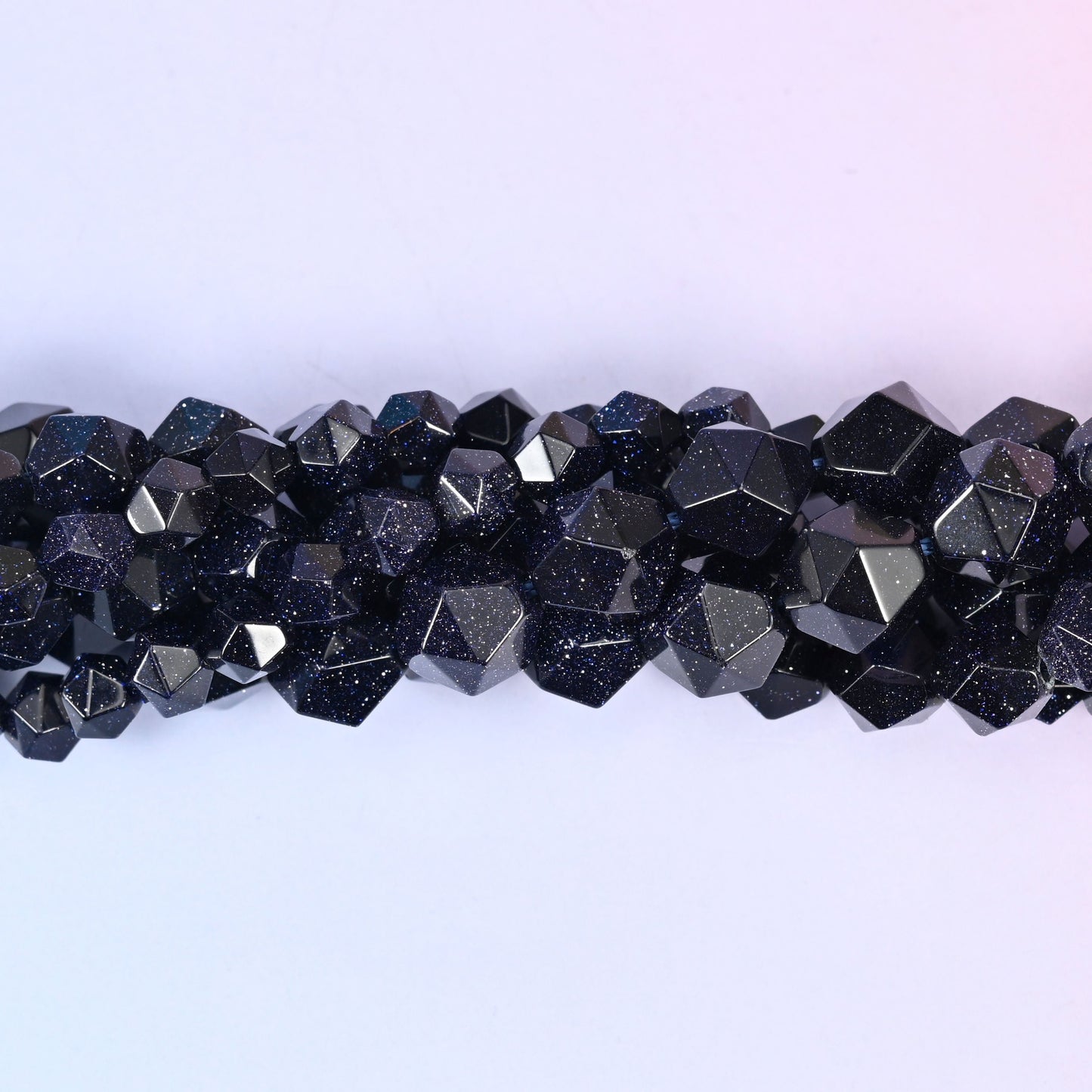 Close-up band of blue sandstone beads where the fine copper glitter flecks catch the light