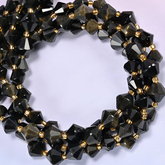 Gold obsidian bicone beads coiled into a round ring of several strands, a warm metallic glow running around the coil.
