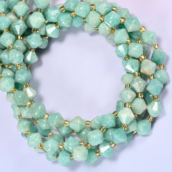 Green Amazonite faceted bicone beads 8mm with gold-tone spacers, strand coiled into a tighter circle, close-up view