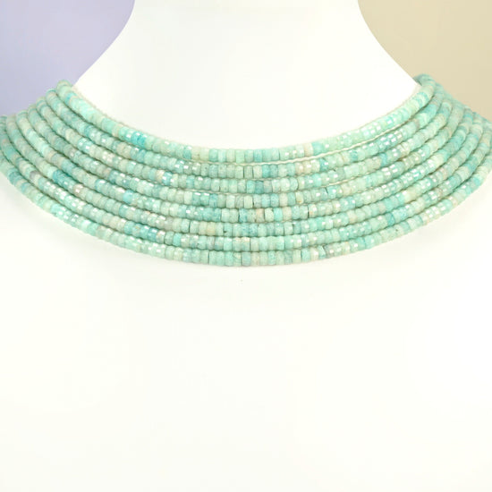 Green amazonite faceted heishi disc strands arranged as a layered collar on a white display bust, light green beads across the neck