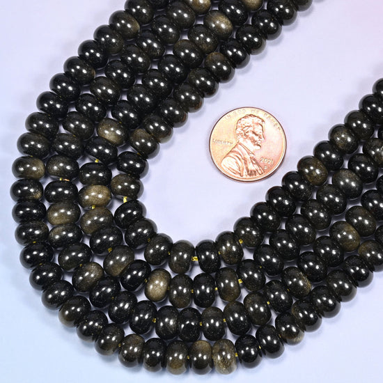 Rows of Gold Obsidian rondelle beads laid straight on a lavender surface, showing the golden sheen variation.