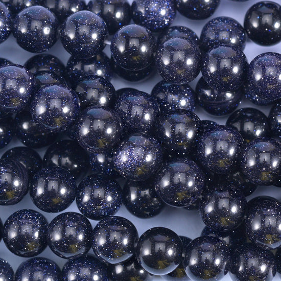 Deep midnight navy rounds packed with fine copper-gold flecks that spark like a night sky when the light moves, finished with a hard mirror polish.