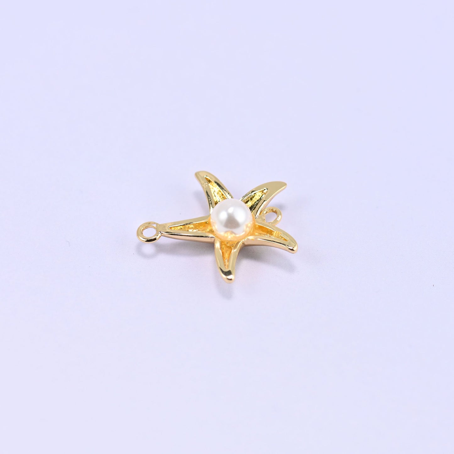 Softly rounded five-arm starfish in polished 18K gold plated brass with a round white pearl centre