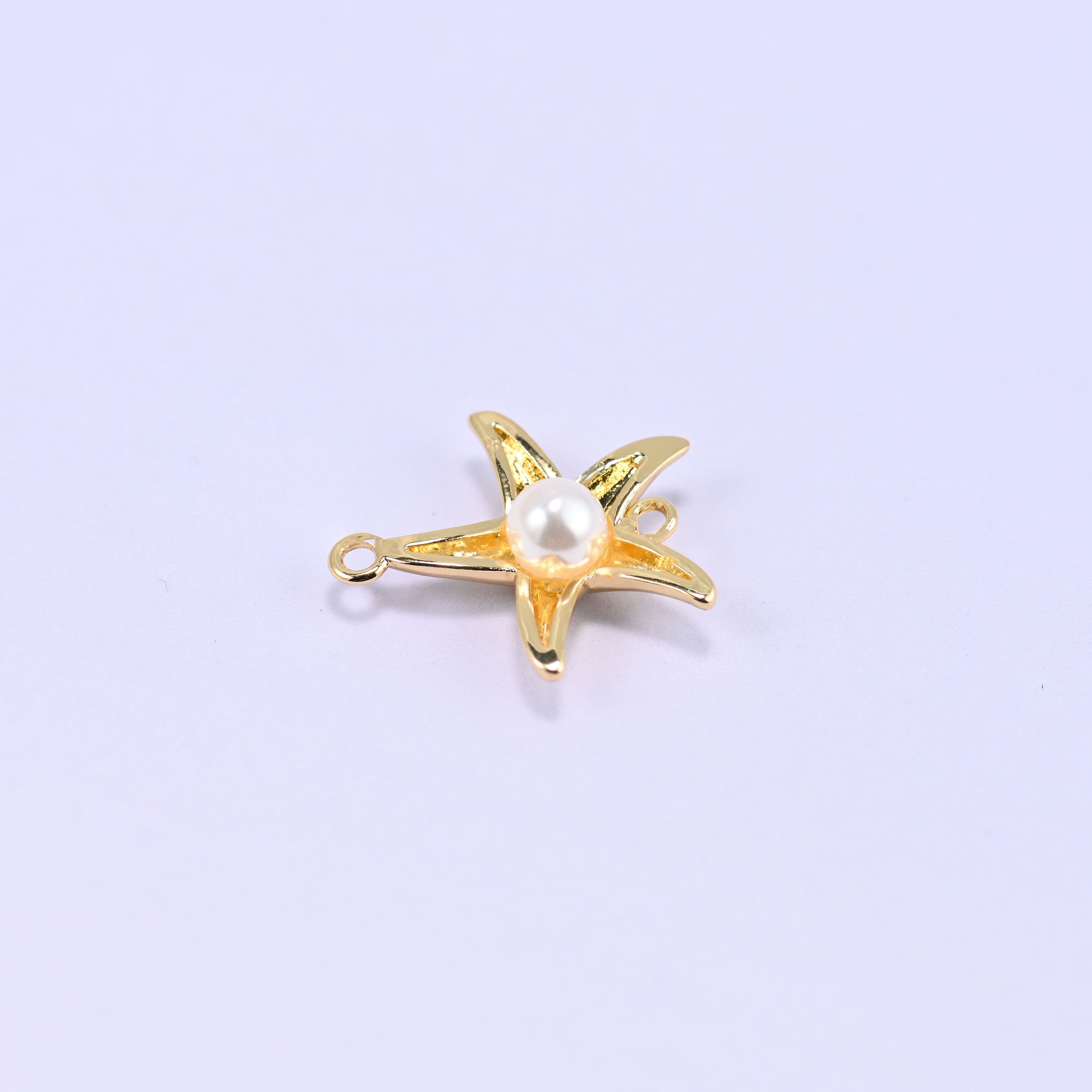 Softly rounded five-arm starfish in polished 18K gold plated brass with a round white pearl centre