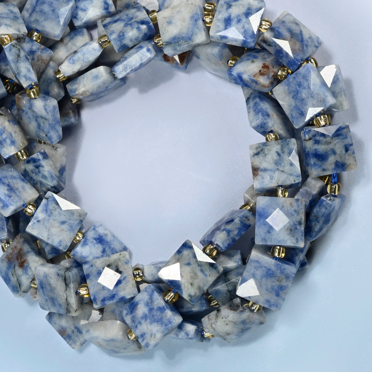 Natural blue spot jasper faceted flat square beads coiled into overlapping loops, whole strands of speckled blue and white stone