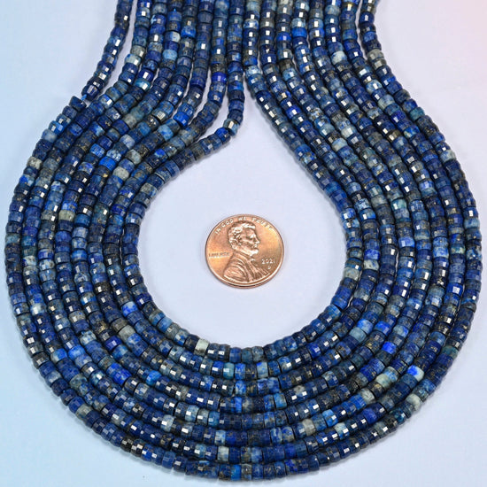 Dark blue lapis faceted heishi disc strands formed into a teardrop loop around a US penny for scale