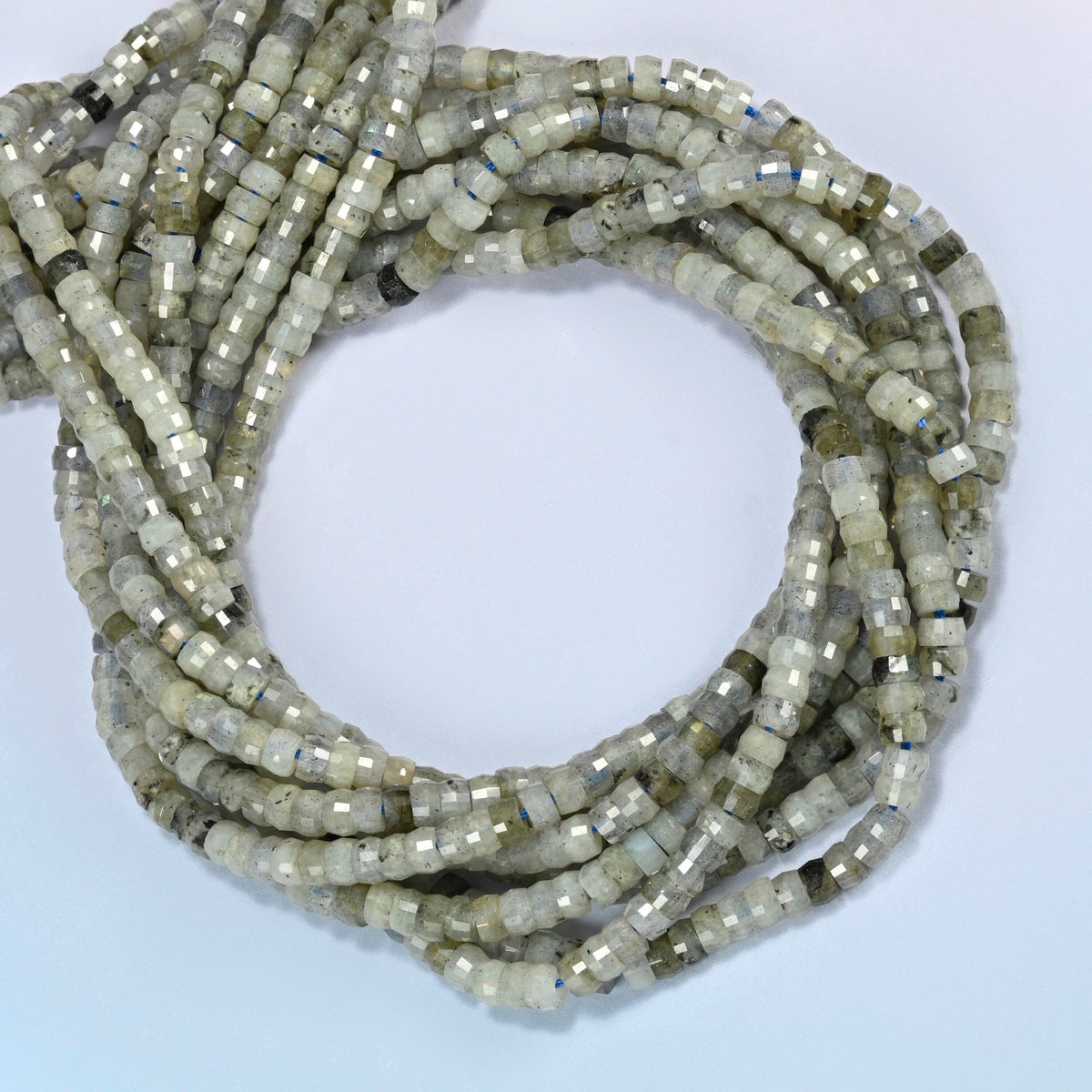 White labradorite faceted heishi disc beads coiled into overlapping loops, whole strands of soft gray-green stone