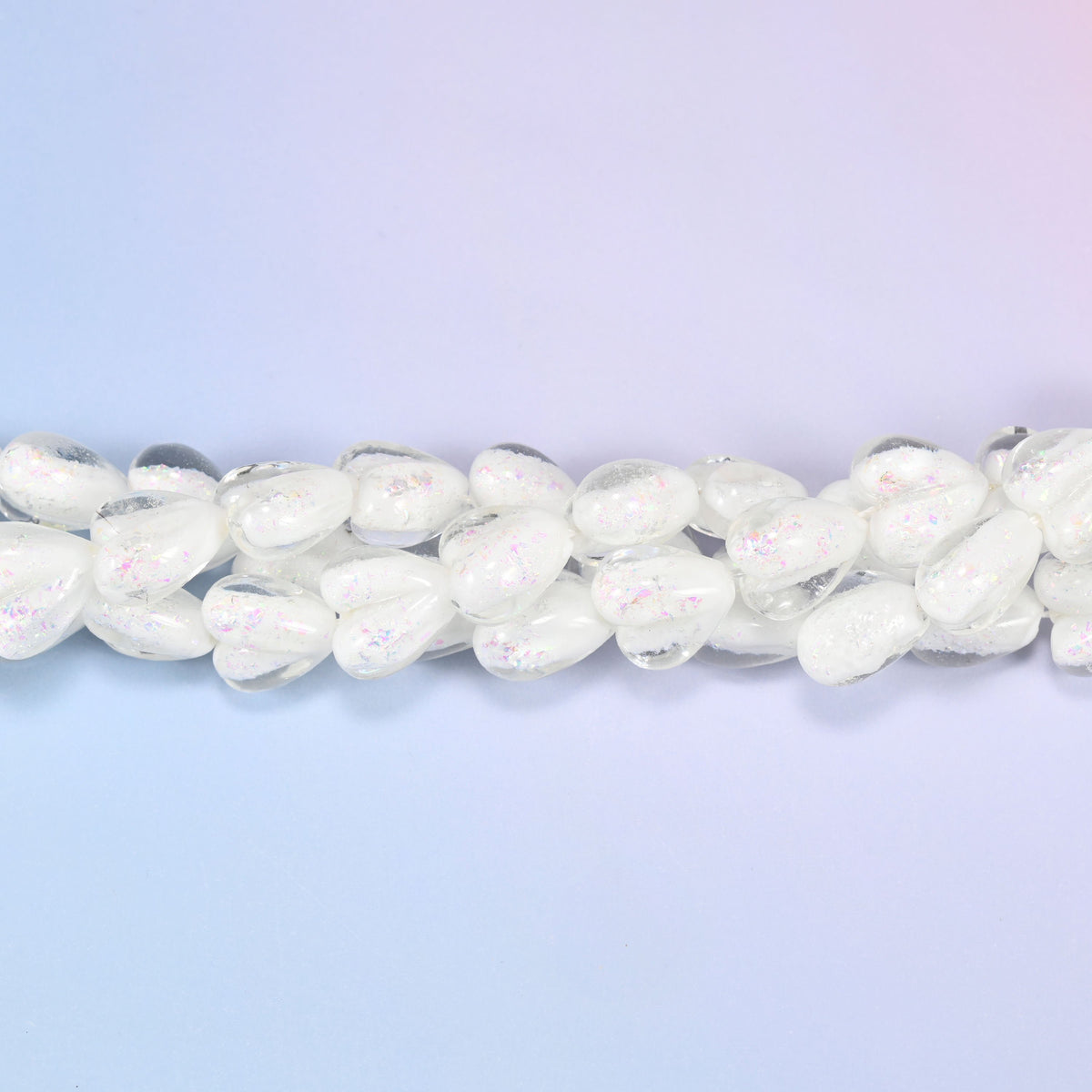 Milky opaque white glass hearts carrying a soft pearly iridescence, closer to freshwater pearl than plain white glass