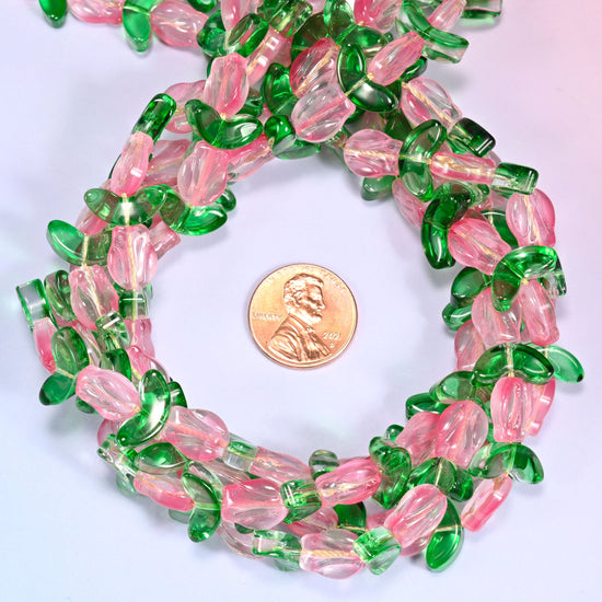 Horizontal row of pink tulip and green leaf glass beads laid straight across a lavender background, showing the alternating flower and leaf pattern.