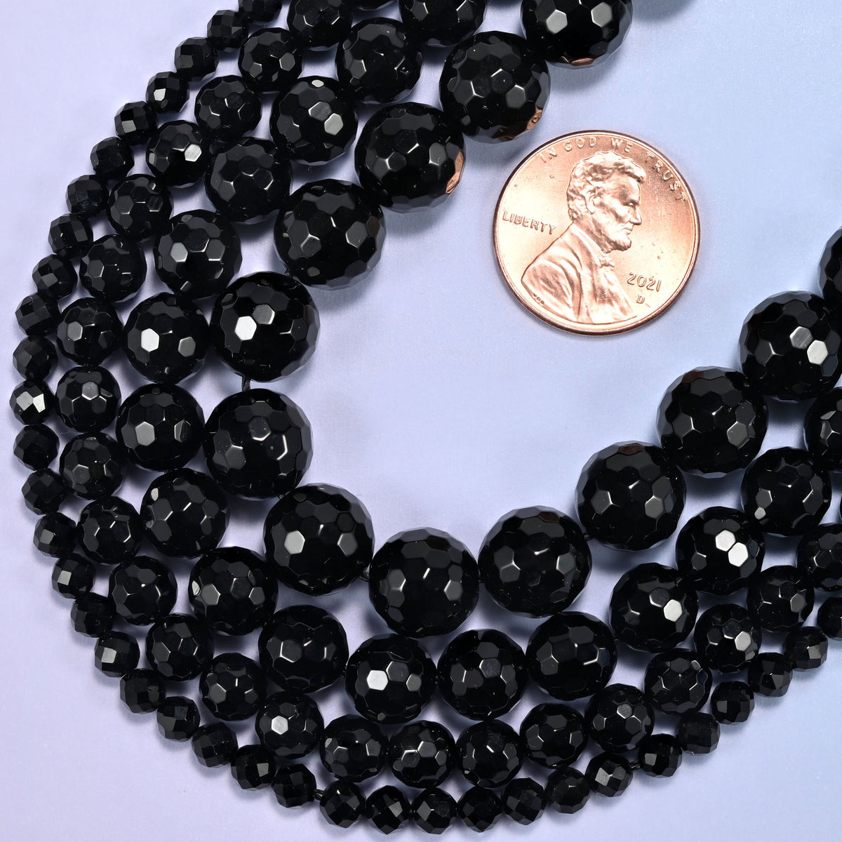 Black onyx faceted round beads looped with a US penny set at the top of the opening.