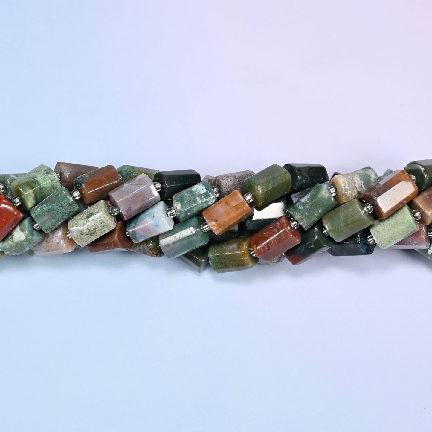 Close-up horizontal row of faceted Indian Agate tube beads showing the multicolor stone pattern and clear glass spacer beads.
