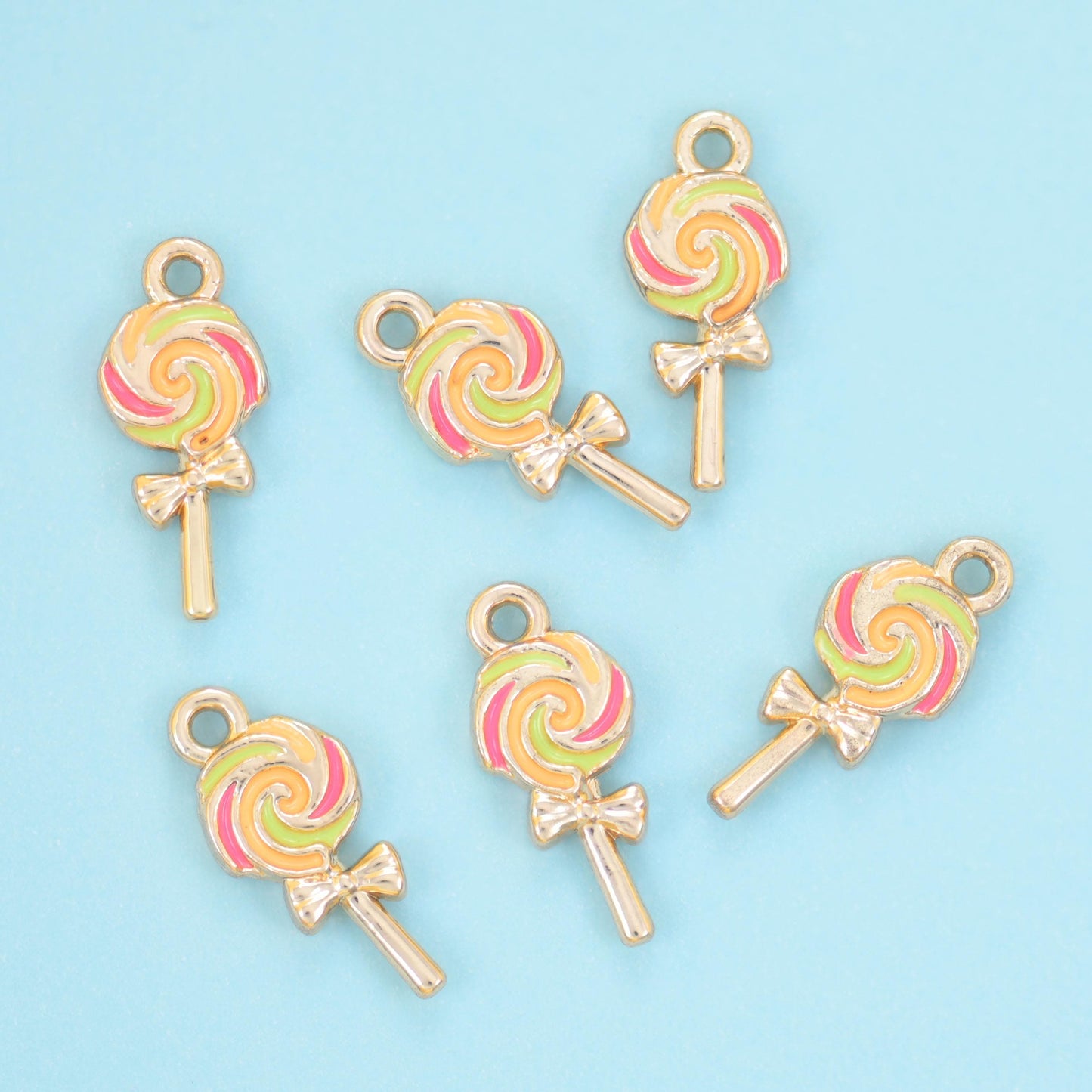 Enamel lollipop charms in a yellow, green and pink swirl, six charms with bow-tied gold sticks.