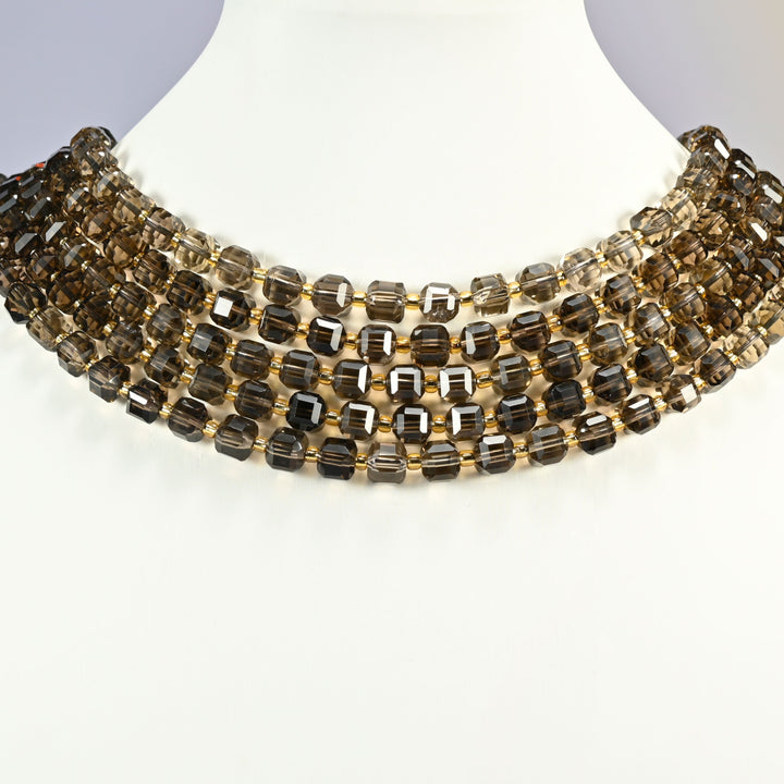 Smoky quartz faceted cube strands arranged as a layered collar across a white display bust.