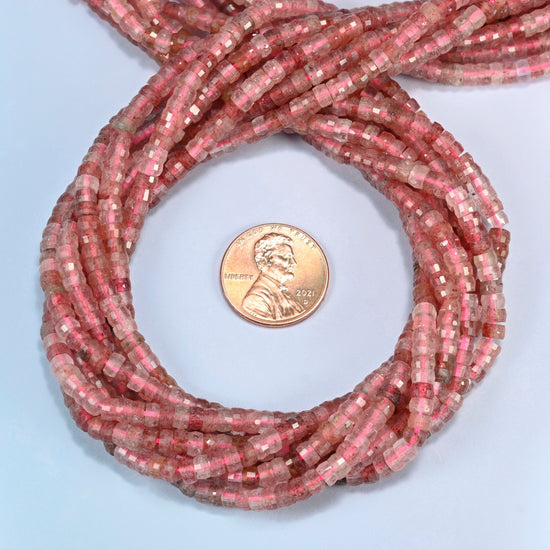 Strawberry quartz faceted heishi disc beads 2x4mm coiled in a loop around a US penny for scale, close-up of the faceted disc shape