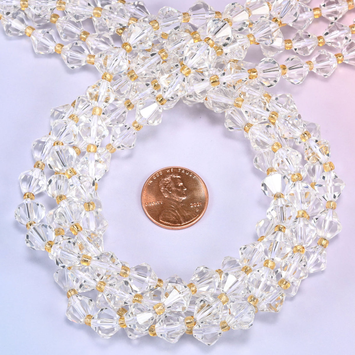Close-up of 8mm Clear Quartz faceted bicone beads coiled into a circle, highlighting the clear transparent color and faceted shape.