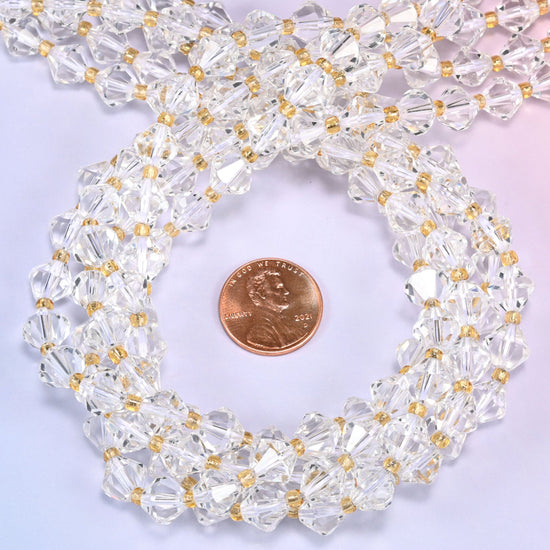 Close-up of 8mm Clear Quartz faceted bicone beads coiled into a circle, highlighting the clear transparent color and faceted shape.