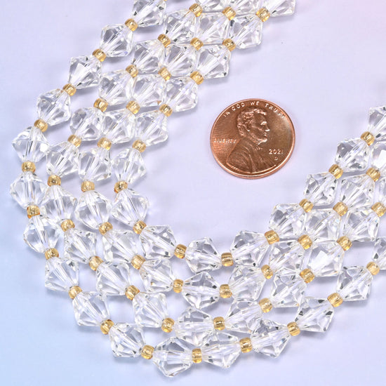 Close-up of 8mm Clear Quartz faceted bicone beads coiled into a circle, showing the clear faceted cut and gold-tone spacer beads.