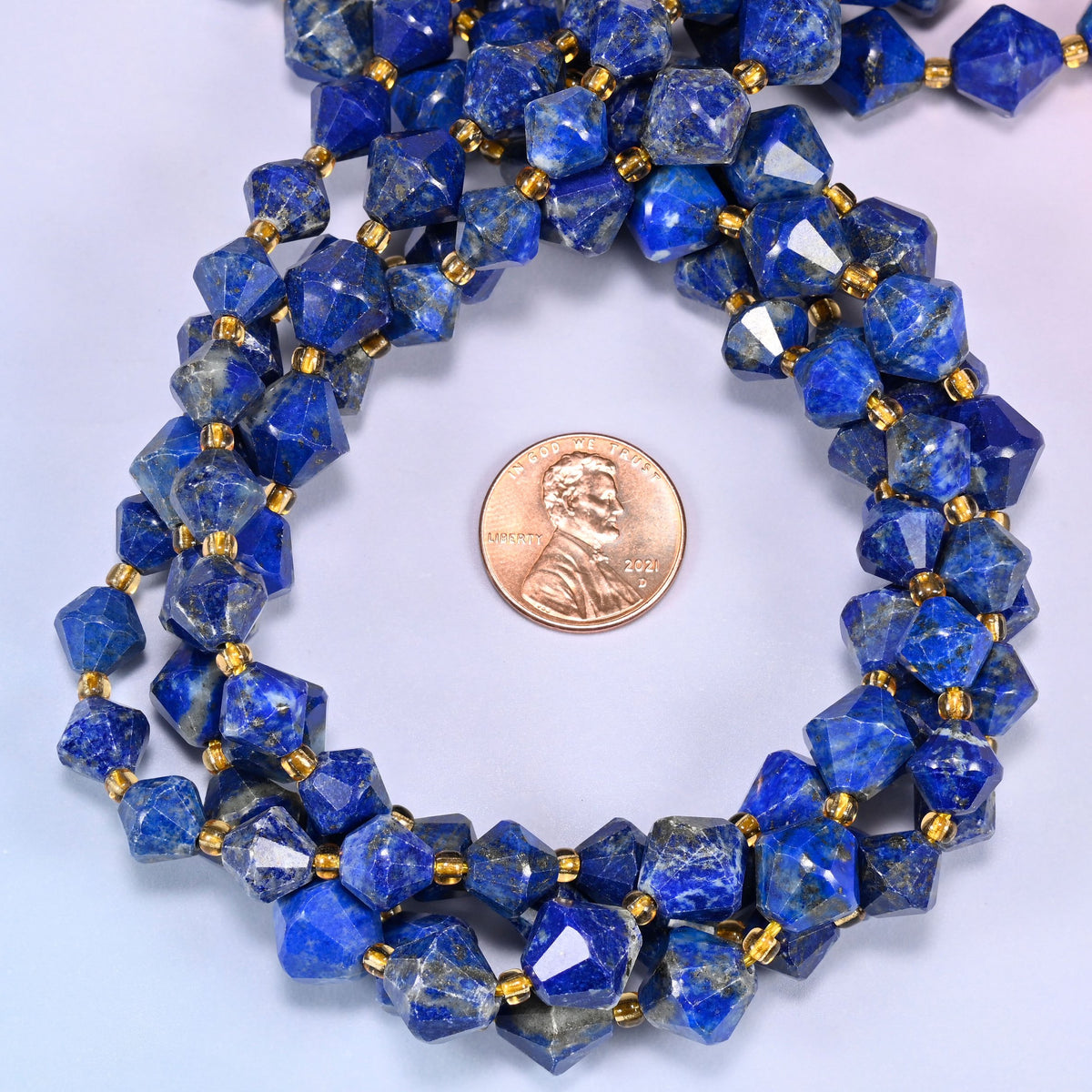 Lapis lazuli bicone beads coiled into a round ring, 8mm and 10mm sizes available, gold-tone spacers throughout.