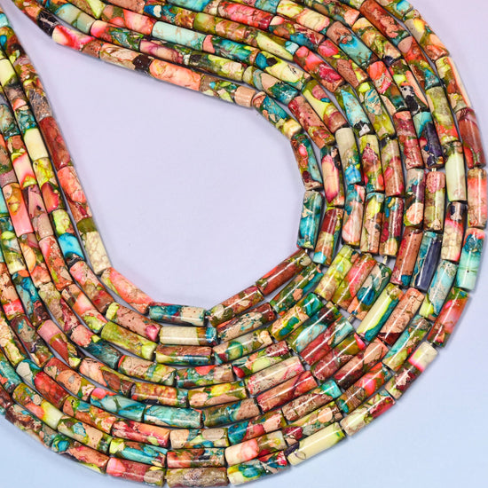 Top-down view of jasper tube bead strands arranged in a loose spiral on a lavender background, highlighting the mix of colors and stone texture.
