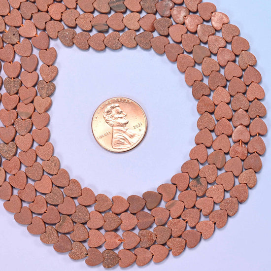 Matte gold sandstone flat heart beads, approximately 68 per strand