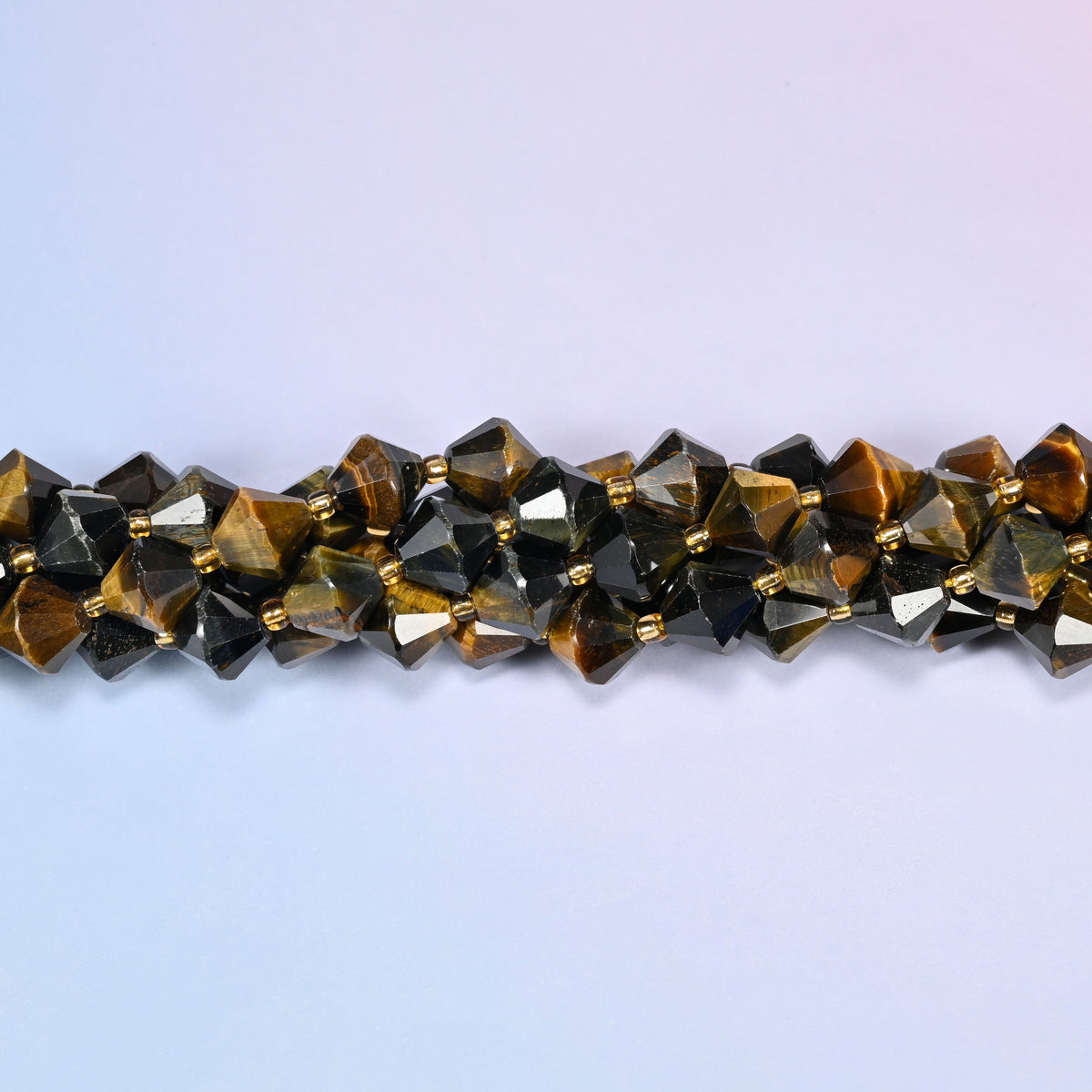 Macro close-up of 10mm Iron Tiger Eye faceted bicone beads on a strand, showing the brown and gold chatoyant banding in detail.