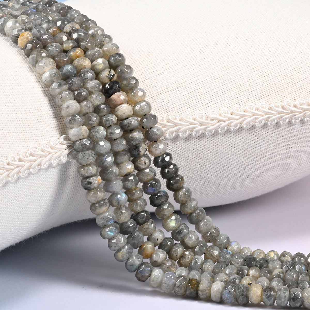 Gray Labradorite faceted rondelle beads draped in a soft curve, light silver gray through smoky charcoal