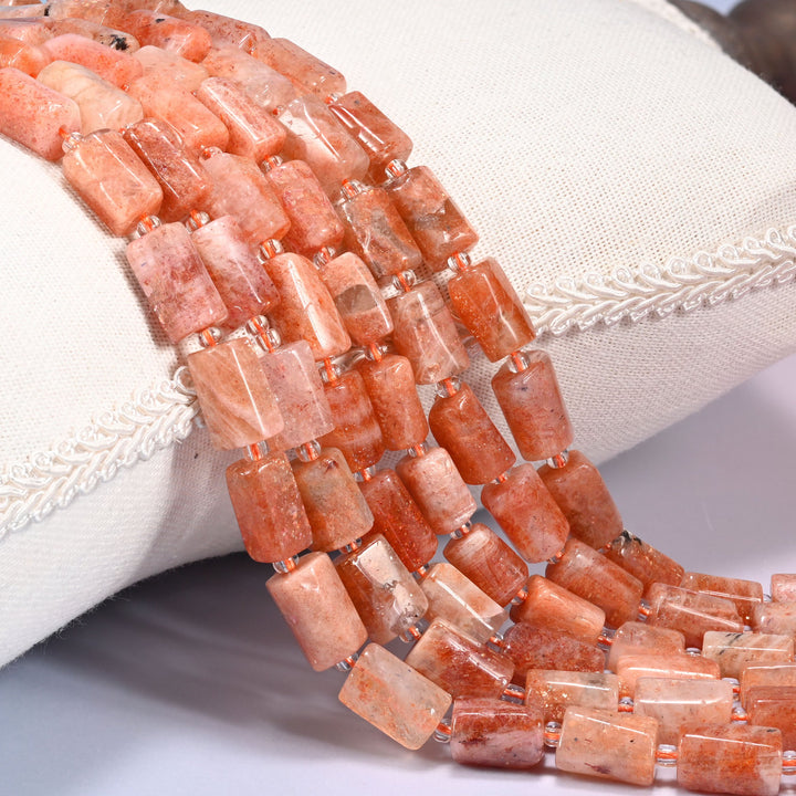 Close-up of multiple strands of faceted Golden Strawberry Quartz tube beads with clear glass spacer beads, draped over a cream fabric jewelry display bust.