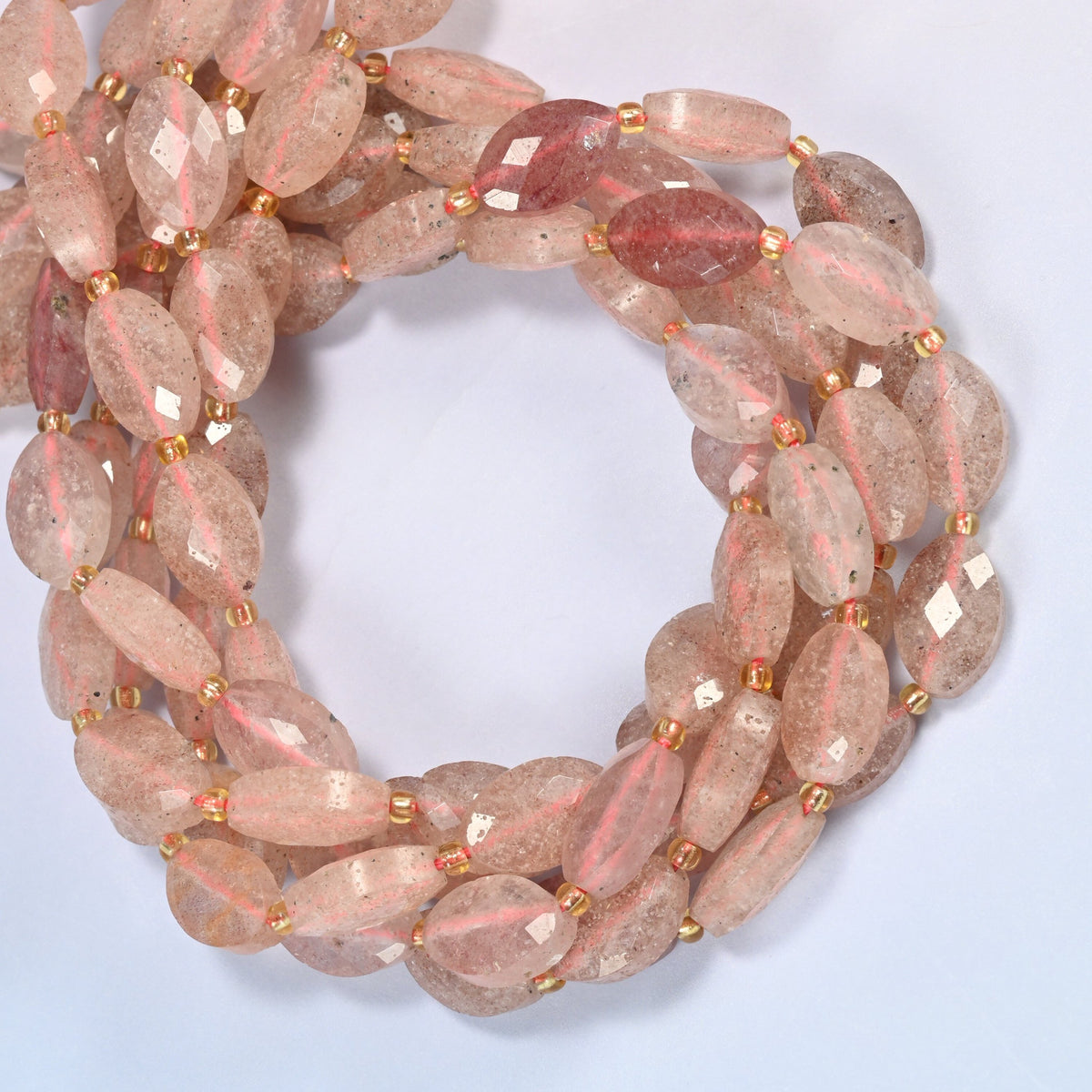 Strawberry quartz faceted flat oval beads coiled into overlapping loops, whole strands of soft pink stone