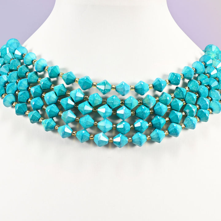Dyed dark blue howlite faceted bicone beads on a white neck display, five strands around the bust.