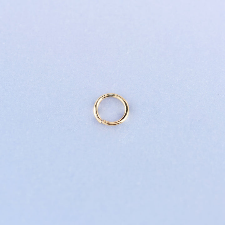 A single 14K gold filled open jump ring shown face on, 5mm across, with the split in the 22 gauge wire visible at the bottom.