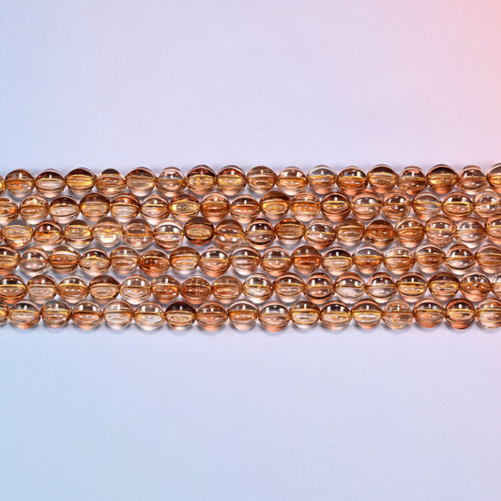 Close-up of 8mm brown pumpkin glass beads in four horizontal rows, showing the carved melon ribs.
