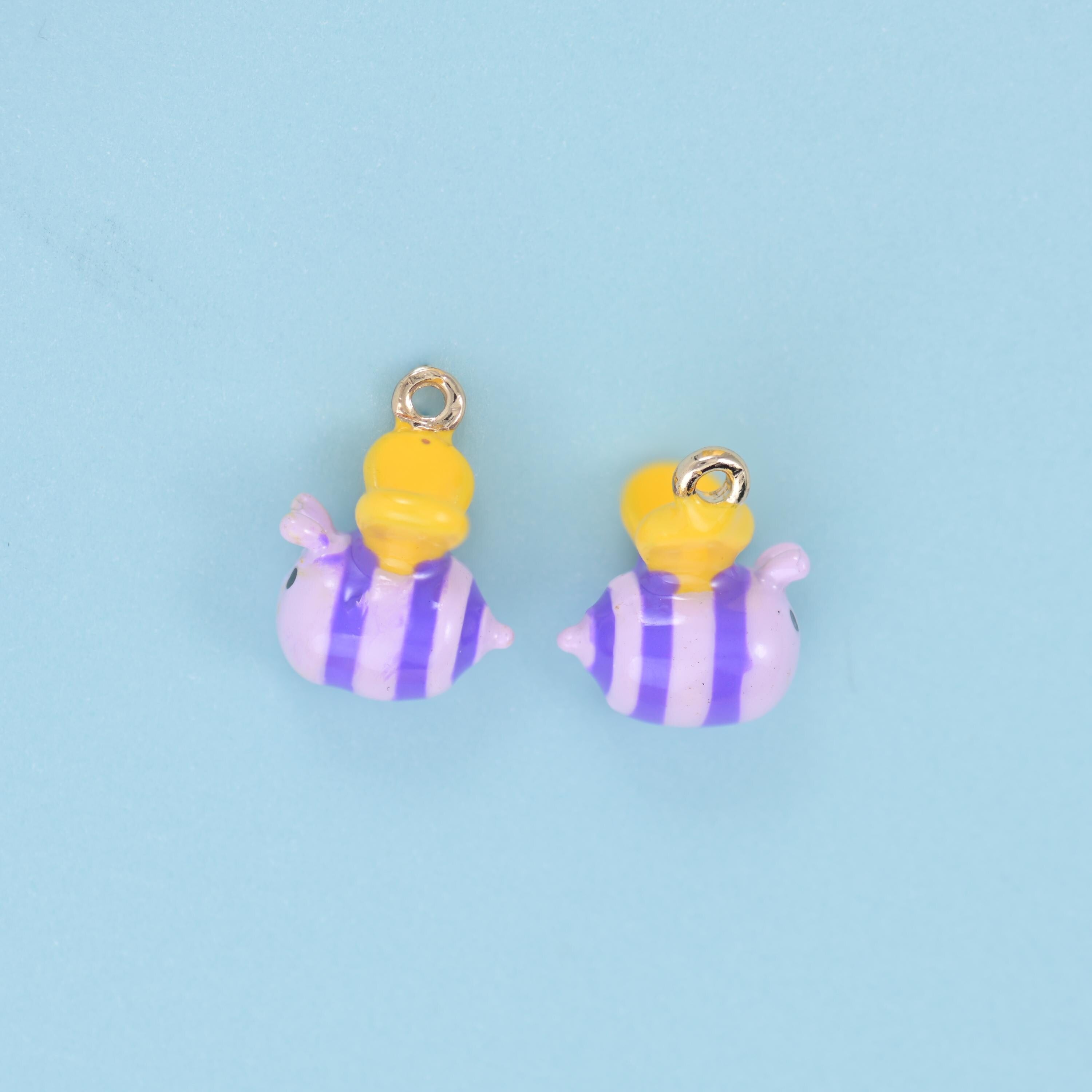 A fat little three-dimensional bee with a striped enamel body, folded wings and a domed head in a contrasting colour