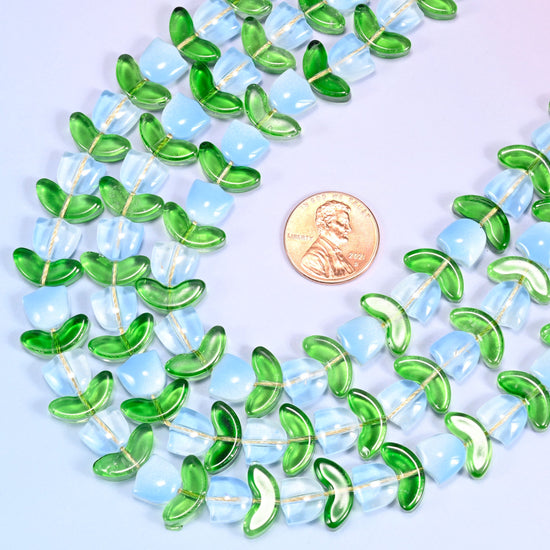 Wide circular coil of light blue tulip and green leaf glass bead strands forming a full wreath shape on a lavender and pink gradient background.