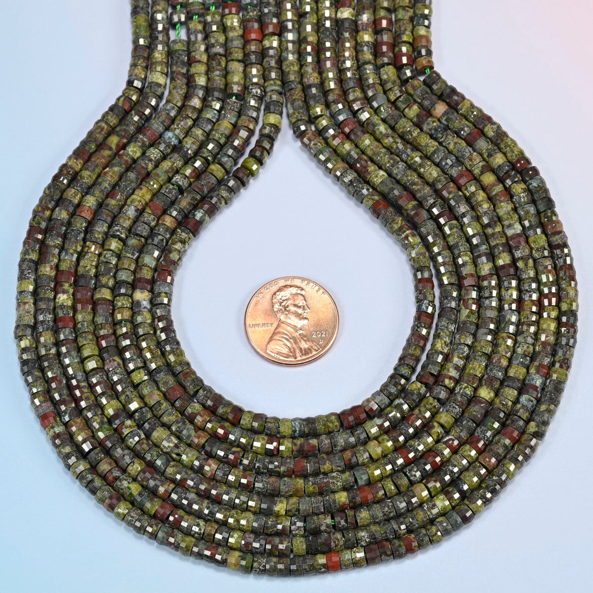 Dragon blood stone faceted heishi disc strands formed into a teardrop loop around a US penny for scale
