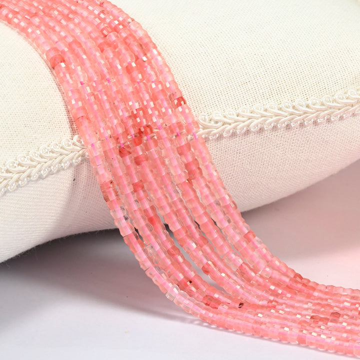 Melon quartz faceted heishi disc beads 2x4mm, several strands draped over a white cushion