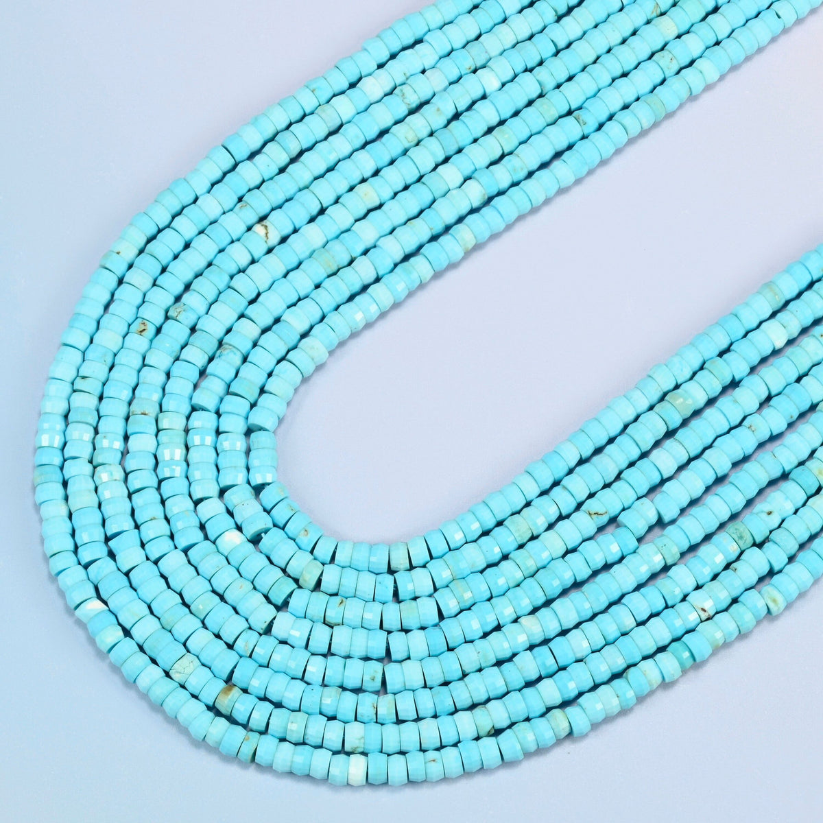 Dyed blue howlite faceted heishi disc beads in several strands curved into a wide U, bright turquoise blue stone with light veining