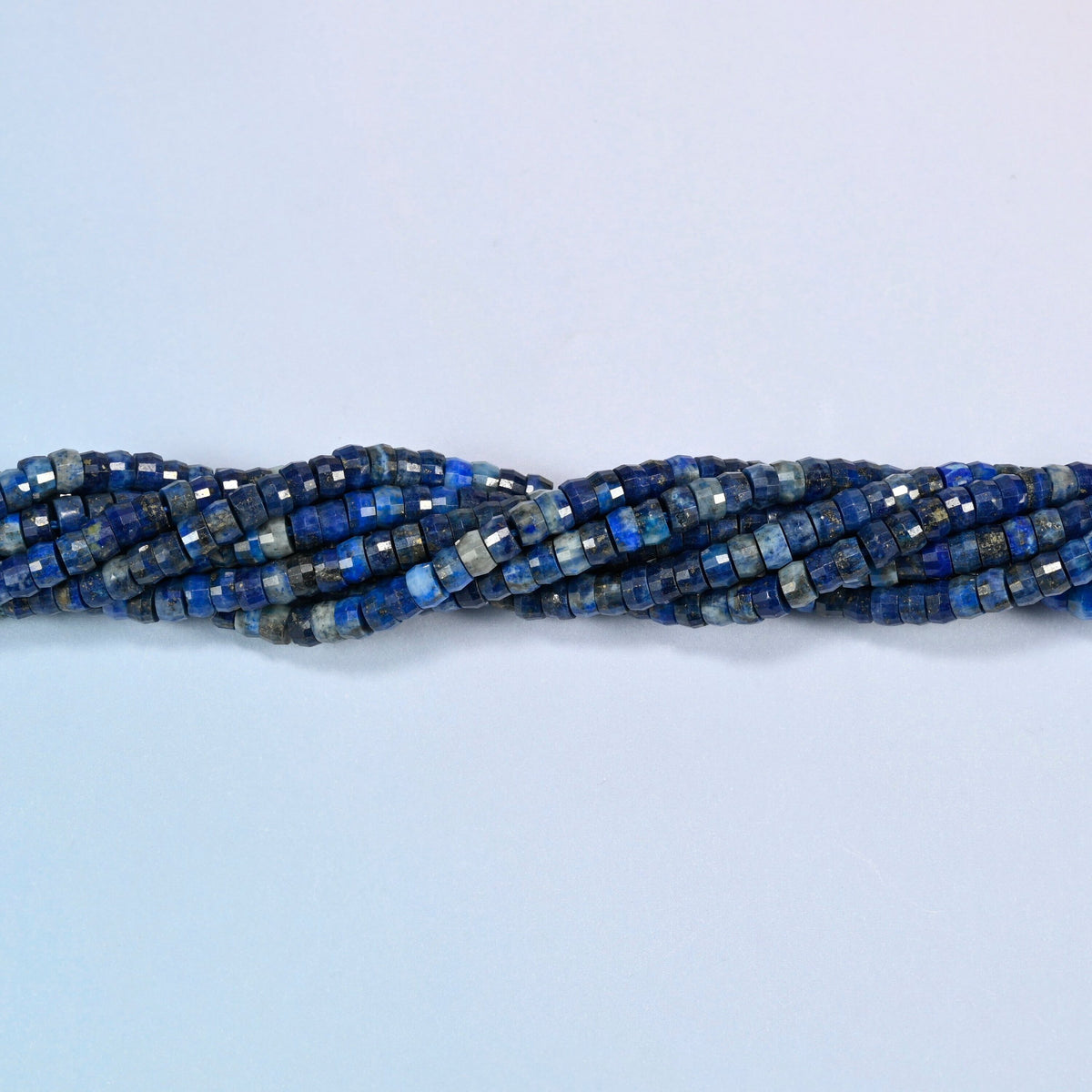 Strands of dark blue lapis faceted heishi disc beads twisted together in a horizontal row