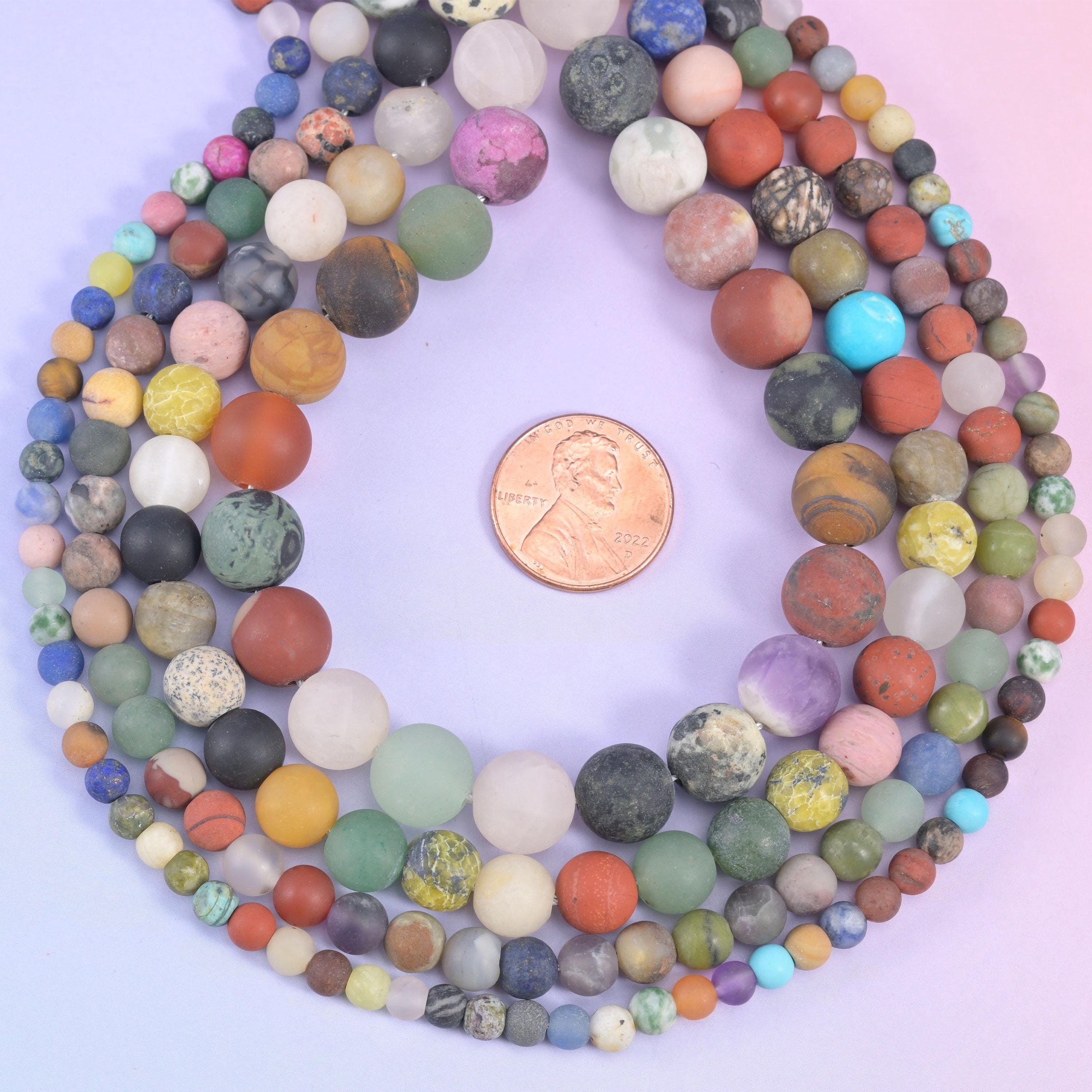 Matte assorted bead strands circling a penny to show the size range
