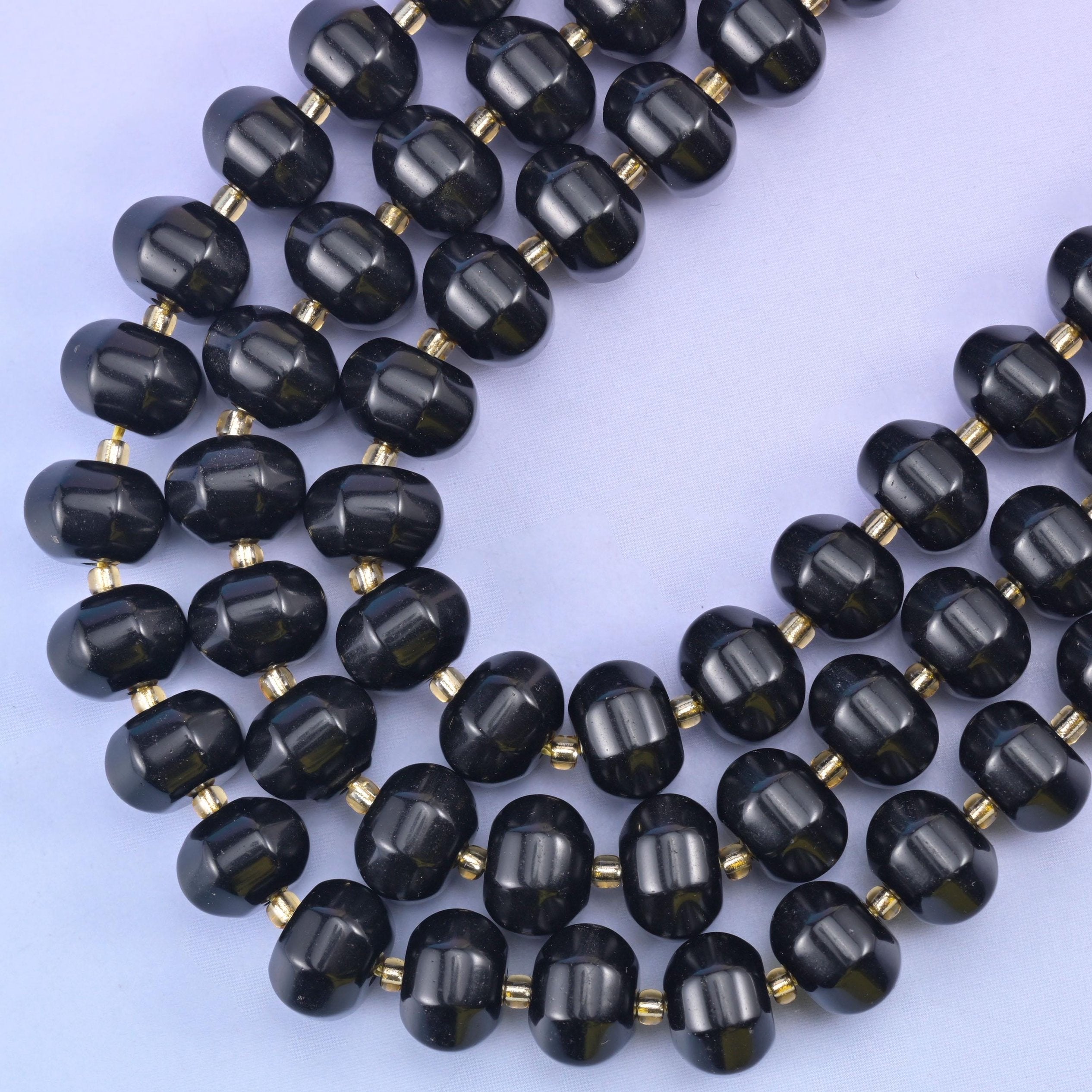 Two strands curving on a soft blue backdrop, the carved melon ribbing clear along every bead